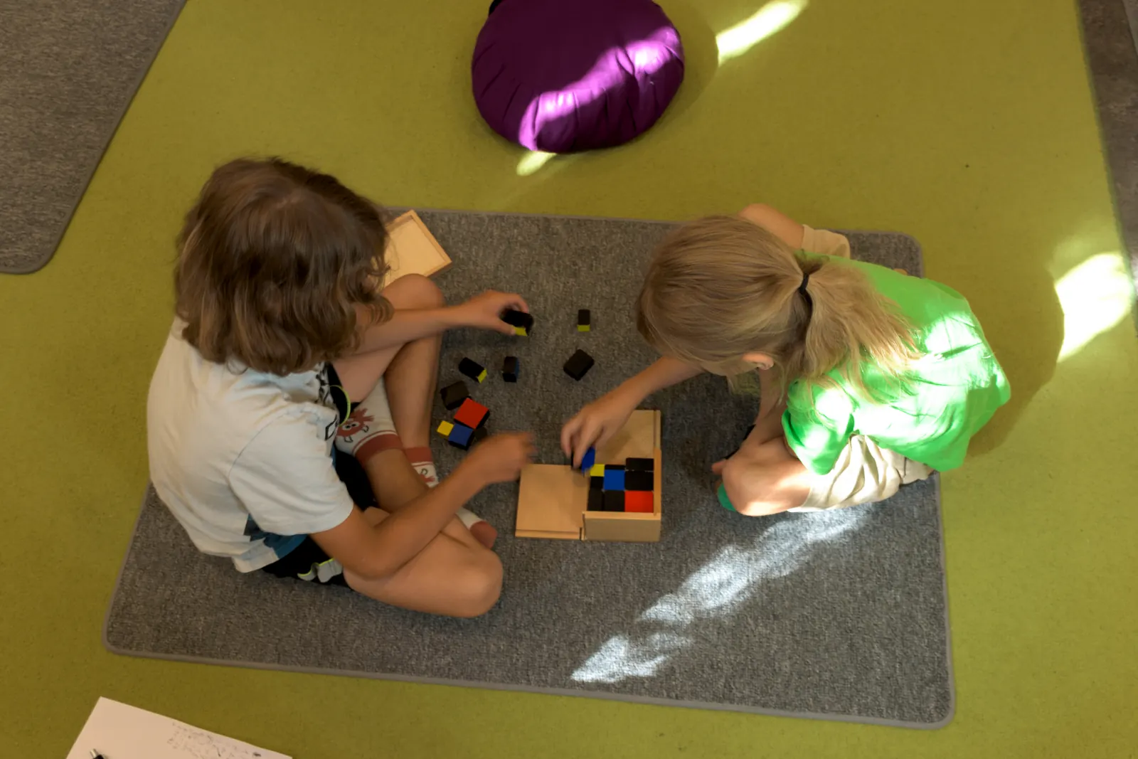 Zwei Kinder bauen konzentriert mit Montessori-Farbwürfeln