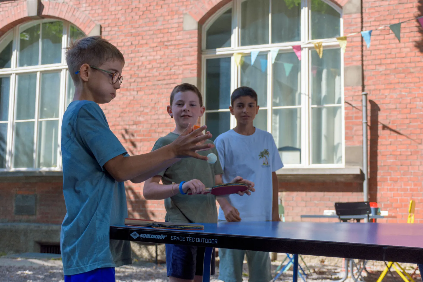 Kinder spielen Tischtennis im Schulhof
