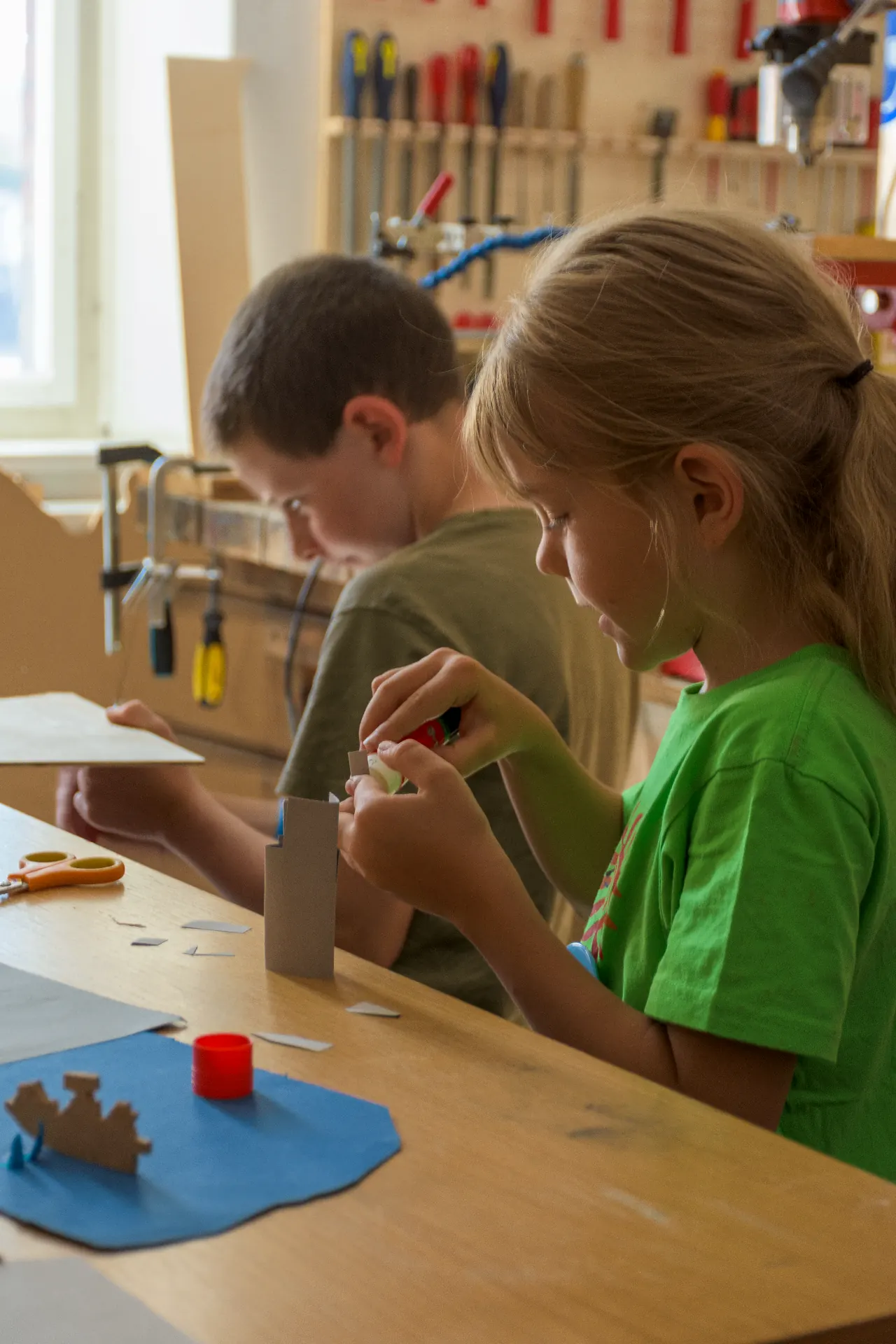 Zwei Kinder basteln konzentriert in der Werkstatt
